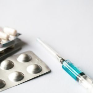 Syringe and pills on a white background isolated, close-up, copy space.